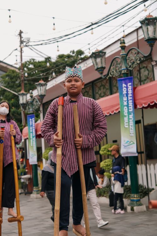 Free Youth performing in traditional attire and stilts during Yogyakarta street parade. Stock Photo