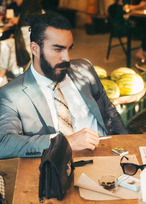 Man Wearing Grey Suit Sitting by the Table