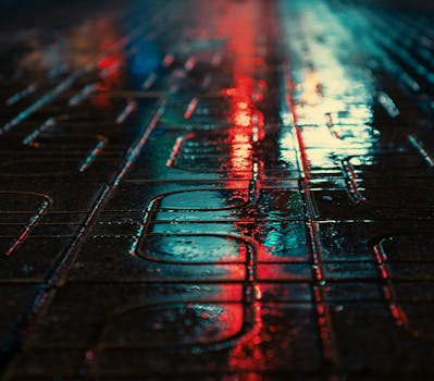 Moody urban street scene with colorful reflections on wet pavement at night.