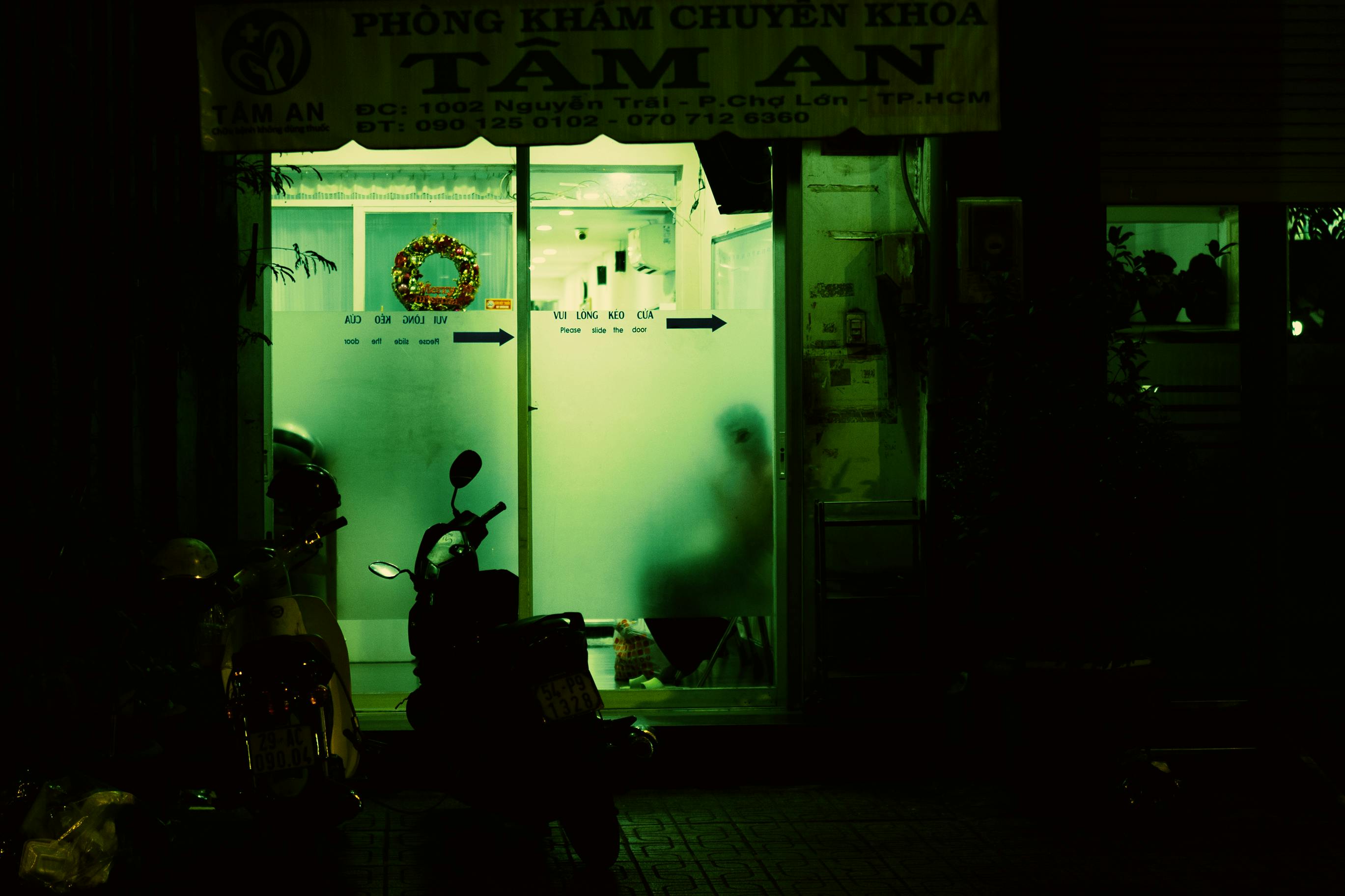 Gratis Pintu masuk klinik yang remang-remang di malam hari dengan sepeda motor terparkir di luar, menciptakan suasana misterius. Foto Stok