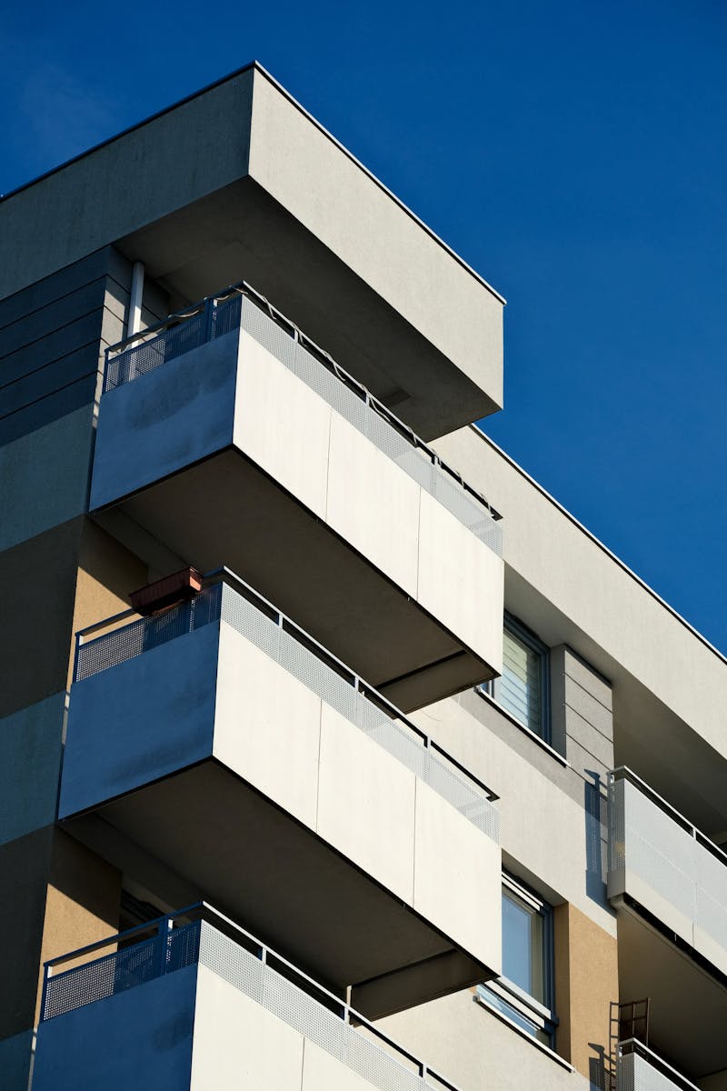 Close-up of a modern apartment building showcasing minimalist design against a clear blue sky.