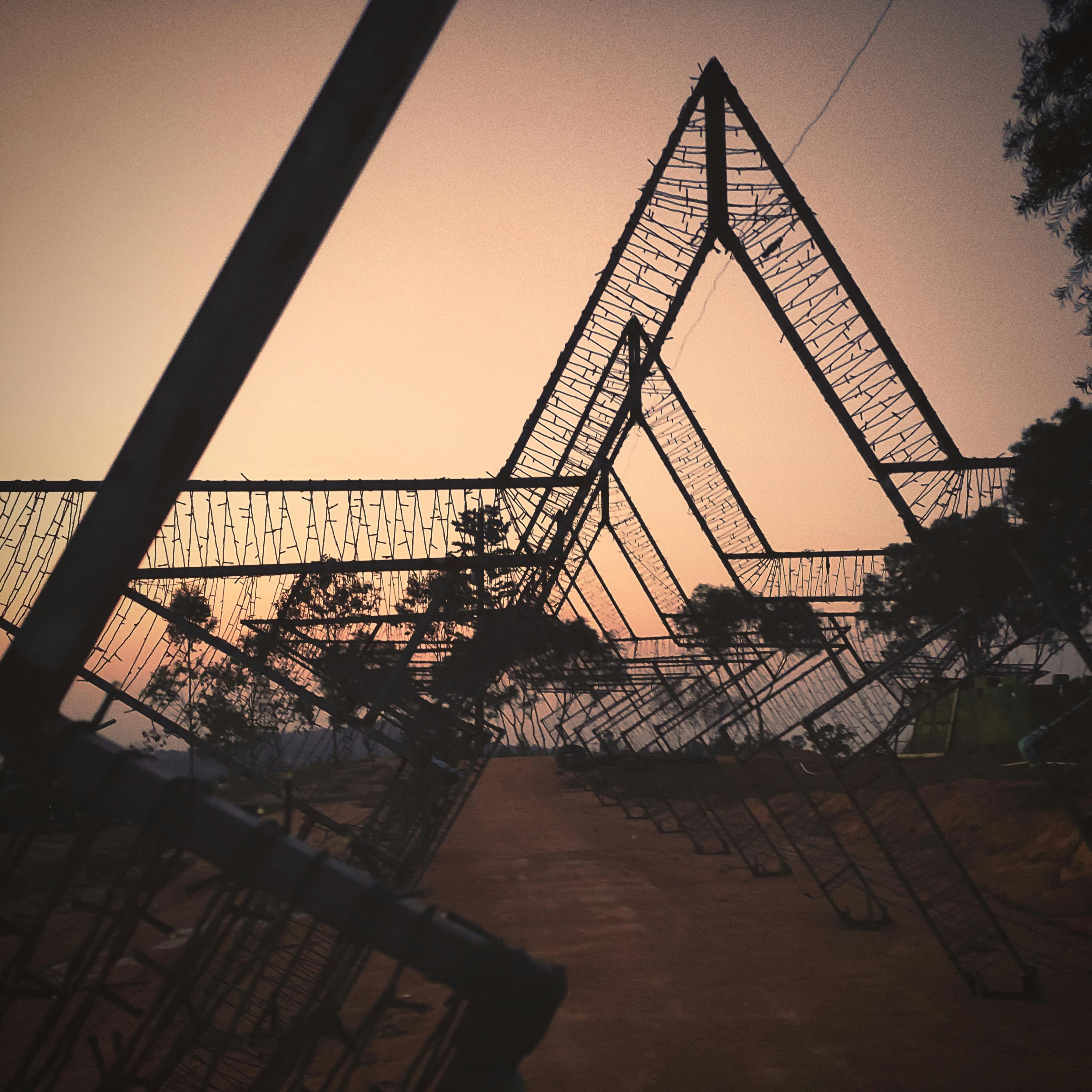 Artistic sunset image with geometric metal structures against a colorful sky.