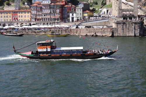 Free A traditional boat cruises on the Douro River with colorful Porto buildings in the background. Stock Photo