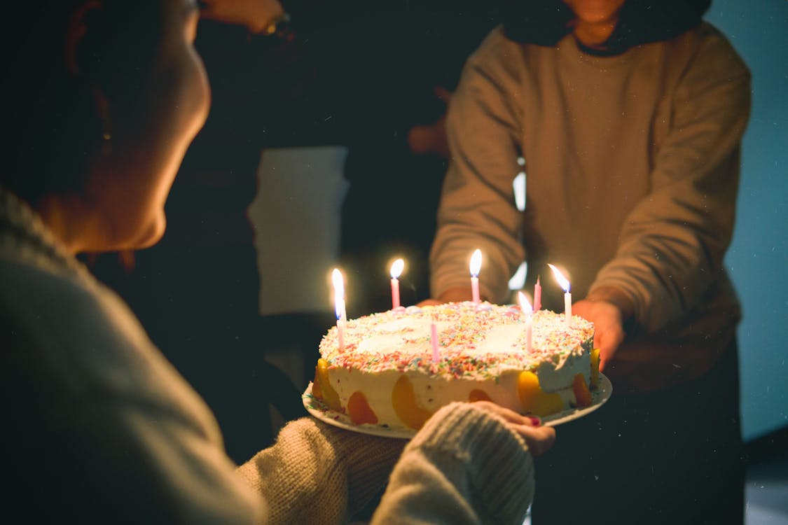 Dua Orang Memegang Kue Dengan Menyalakan Lilin