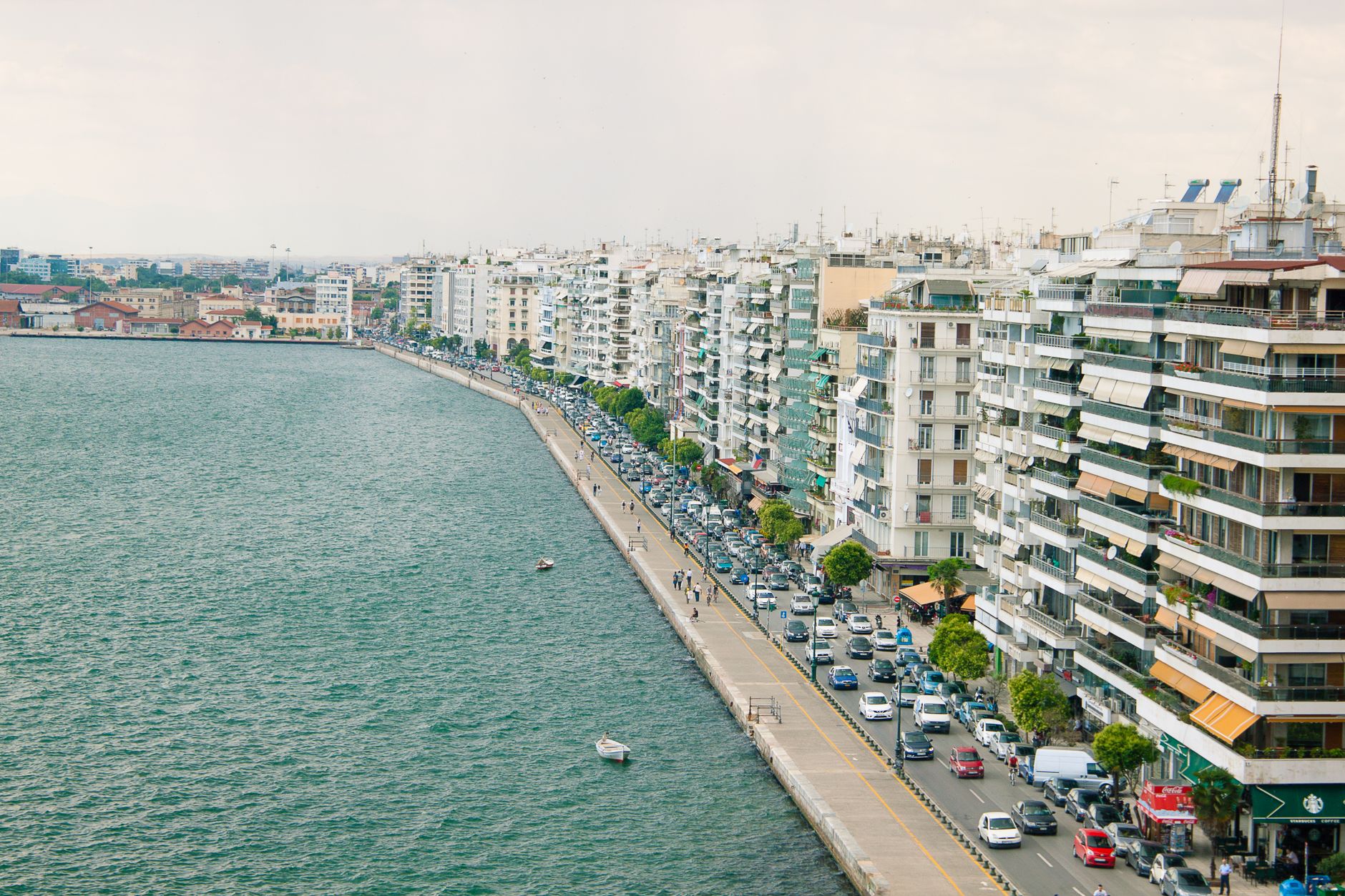 Aerial view of a bustling waterfront with high-rise buildings lining the street, showcasing urban life. — photo by Ami Suhzu / Pexels