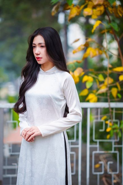 Elegant Vietnamese woman in a white áo dài in Ho Chi Minh City garden.