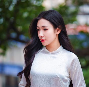 Beautiful woman wearing a white Áo Dài, captured outdoors in Ho Chi Minh City.