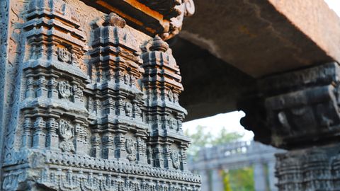 Detailed Indian temple carvings on stone pillars, showcasing ancient architectural art.