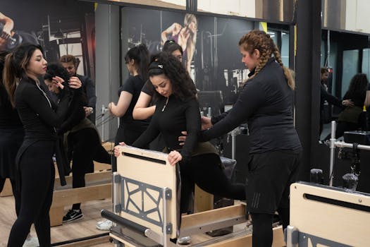 Women practicing Pilates in a gym setting with a trainer, emphasizing fitness and teamwork.