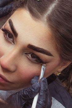 Detailed shot of eye shadow application on a woman's eyes by a professional makeup artist.
