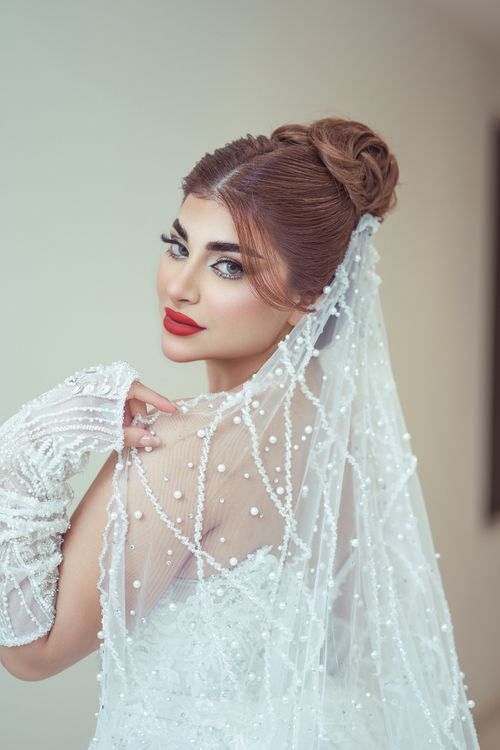 Free Beautiful bride in a pearled veil looking over shoulder with elegant hairstyle and makeup. Stock Photo
