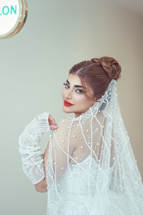Free Beautiful bride in a pearl-embellished gown with a chic updo, captured indoors with a vintage feel. Stock Photo