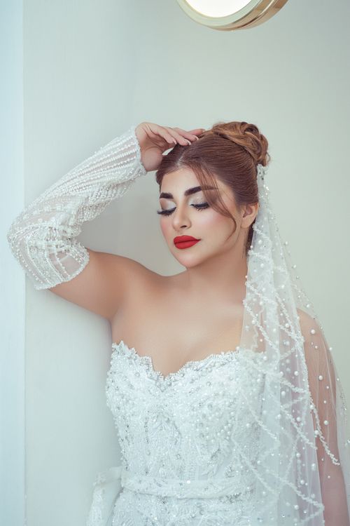 Free A stunning bride in a beaded wedding dress with glamorous red lipstick posing indoors. Stock Photo