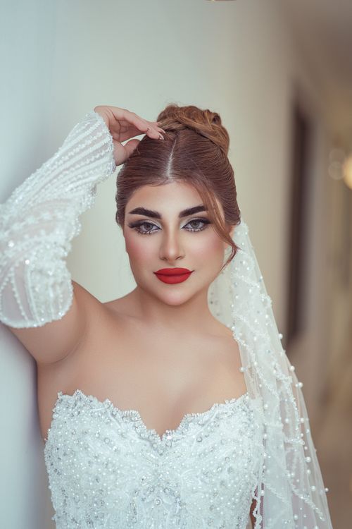 Free Beautiful bride poses in an intricate beaded gown and veil indoors, showcasing elegance. Stock Photo