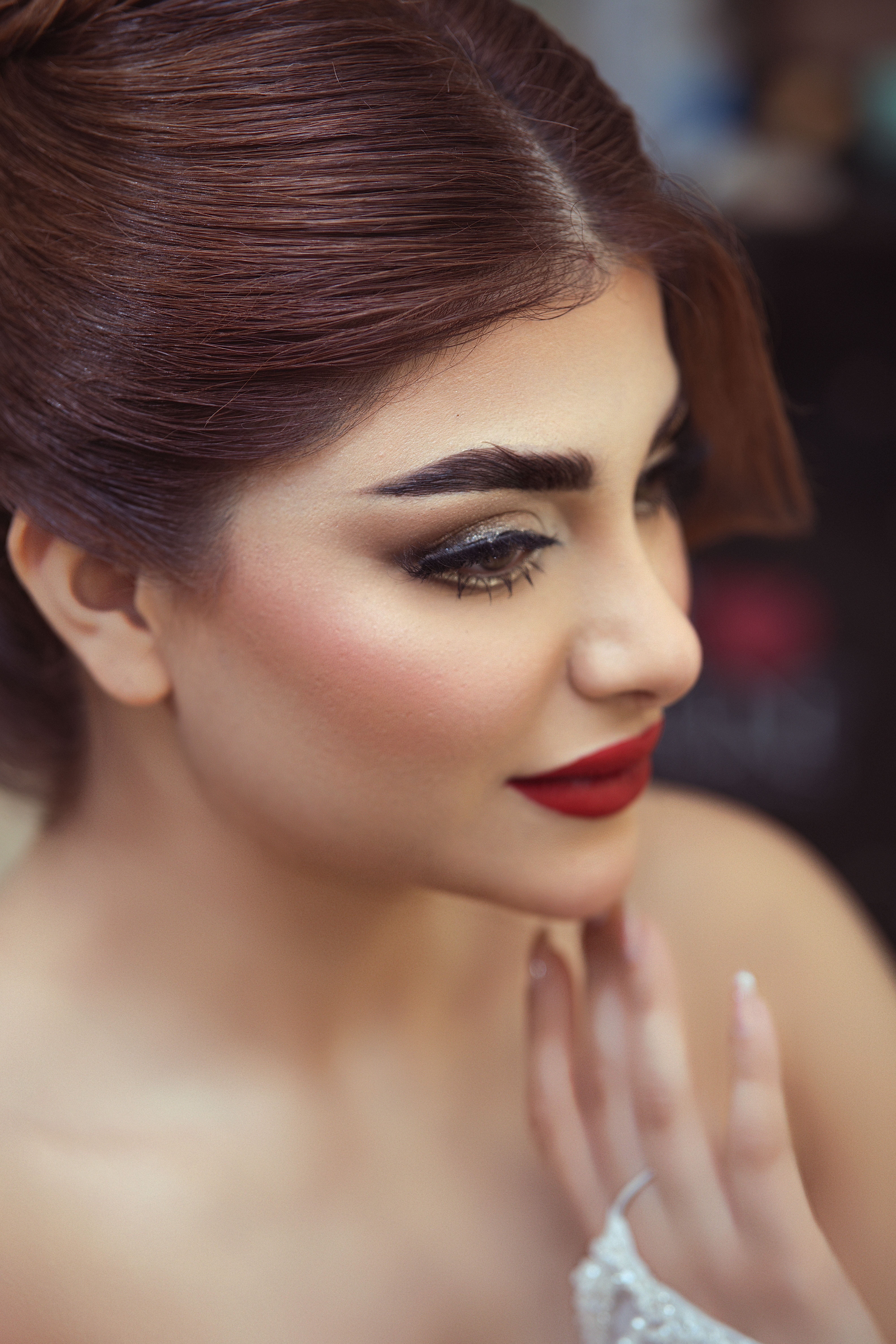 Close-up portrait of an elegant woman with stunning makeup and red lips, exuding glamour.