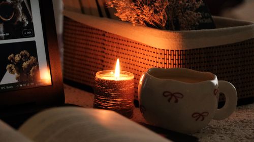 Free Warm candlelit scene with a digital book and tea for a cozy atmosphere. Stock Photo