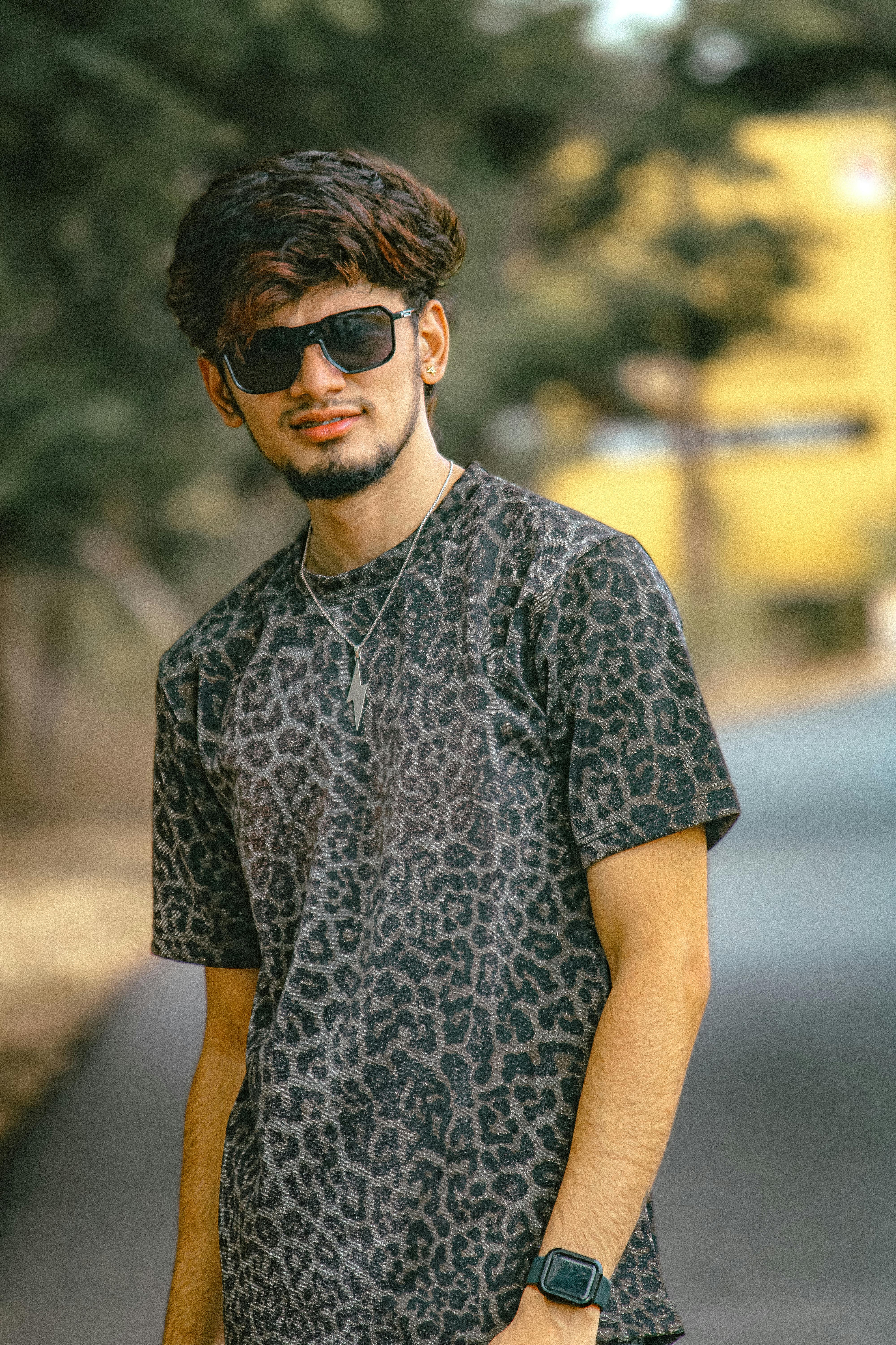 免費 一名身穿動物紋襯衫、戴著墨鏡的年輕男子自信地站在路邊。 圖庫相片