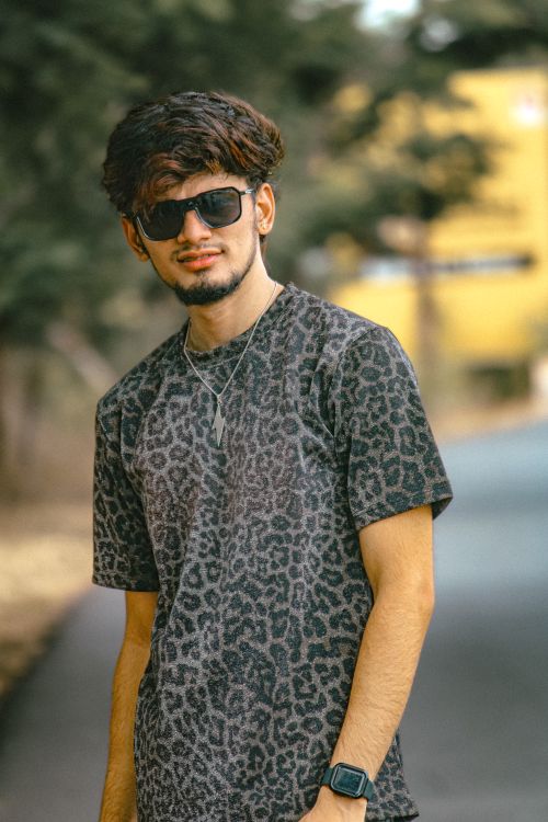 Free Young man wearing animal print shirt and sunglasses, standing confidently on a roadside. Stock Photo
