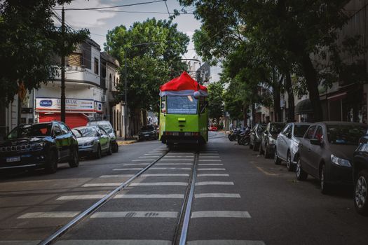 A vibrant green tram with a Santa hat in Buenos Aires, Argentina, surrounded by city life.