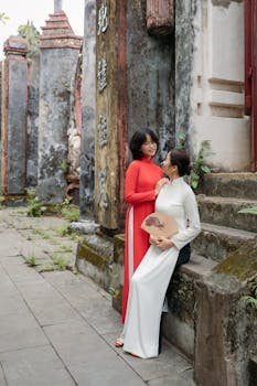 Two women in traditional Ao Dai dresses at a historic site in Hội An, Vietnam.