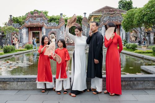 Free Family wearing traditional attire with fans at a temple in Hội An, Vietnam. Stock Photo