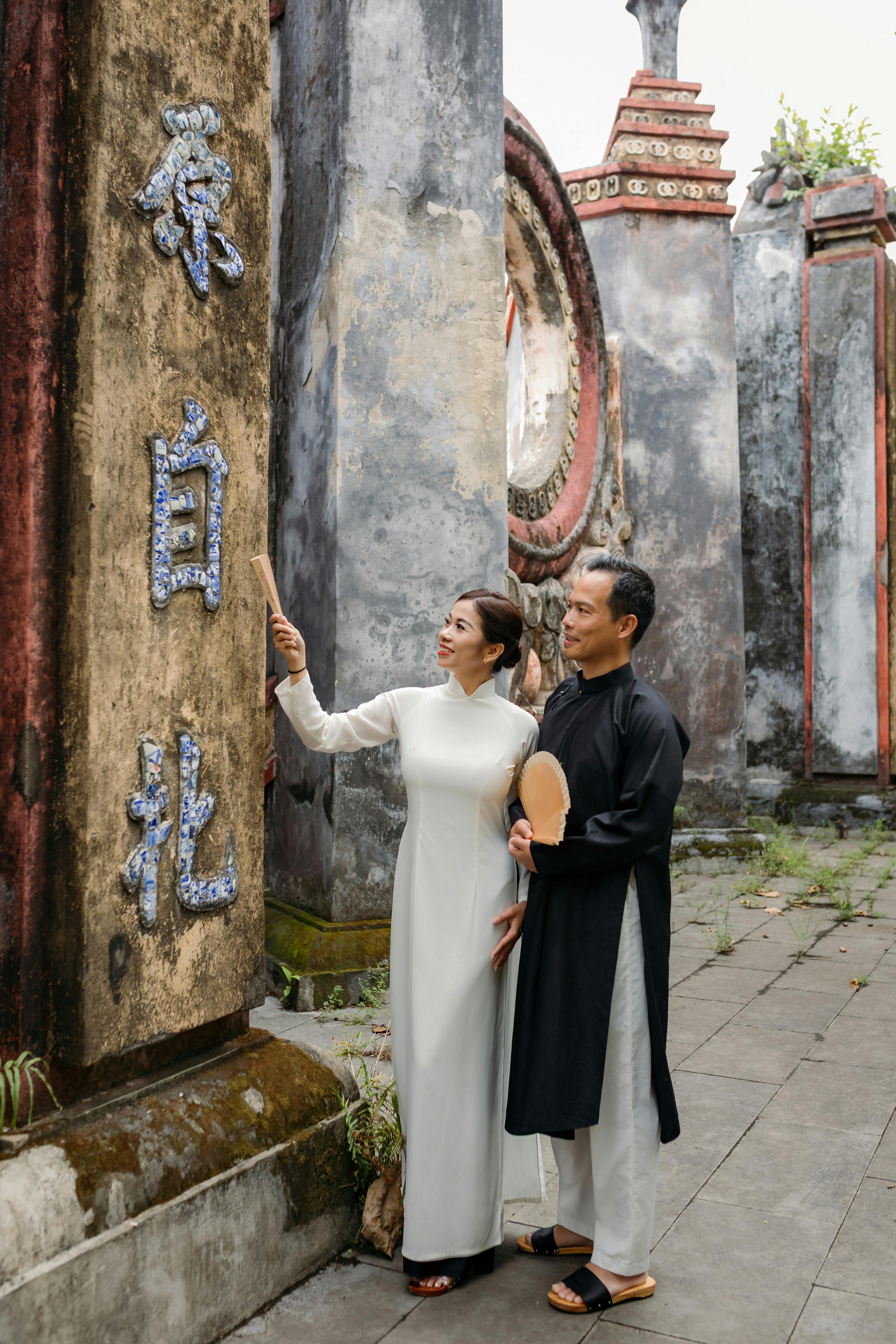A couple in traditional áo dài exploring an ancient site in Hội An, Vietnam.