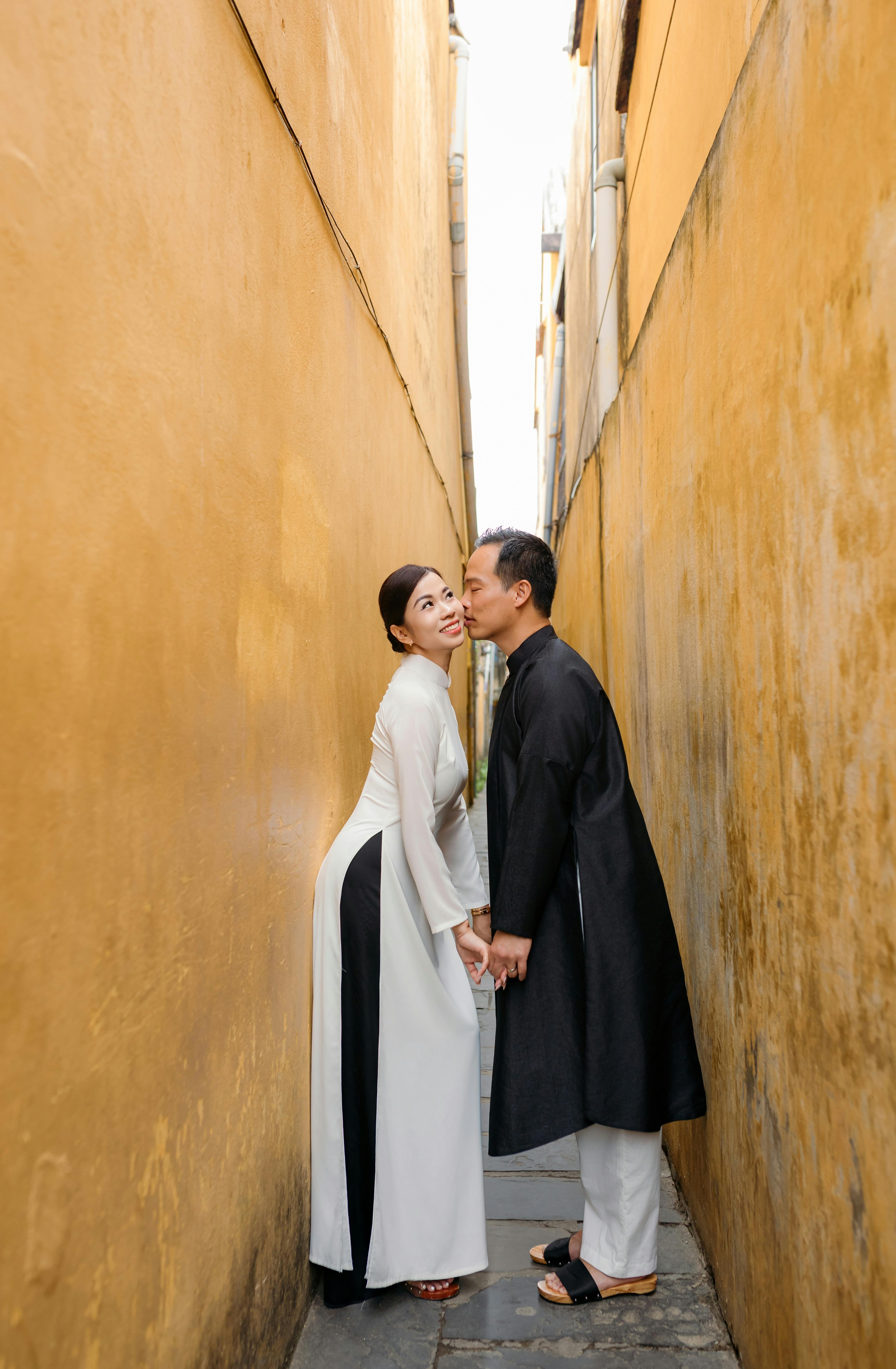 Romantic couple pose wearing traditional attire in a narrow alleyway of Hoi An, Vietnam.