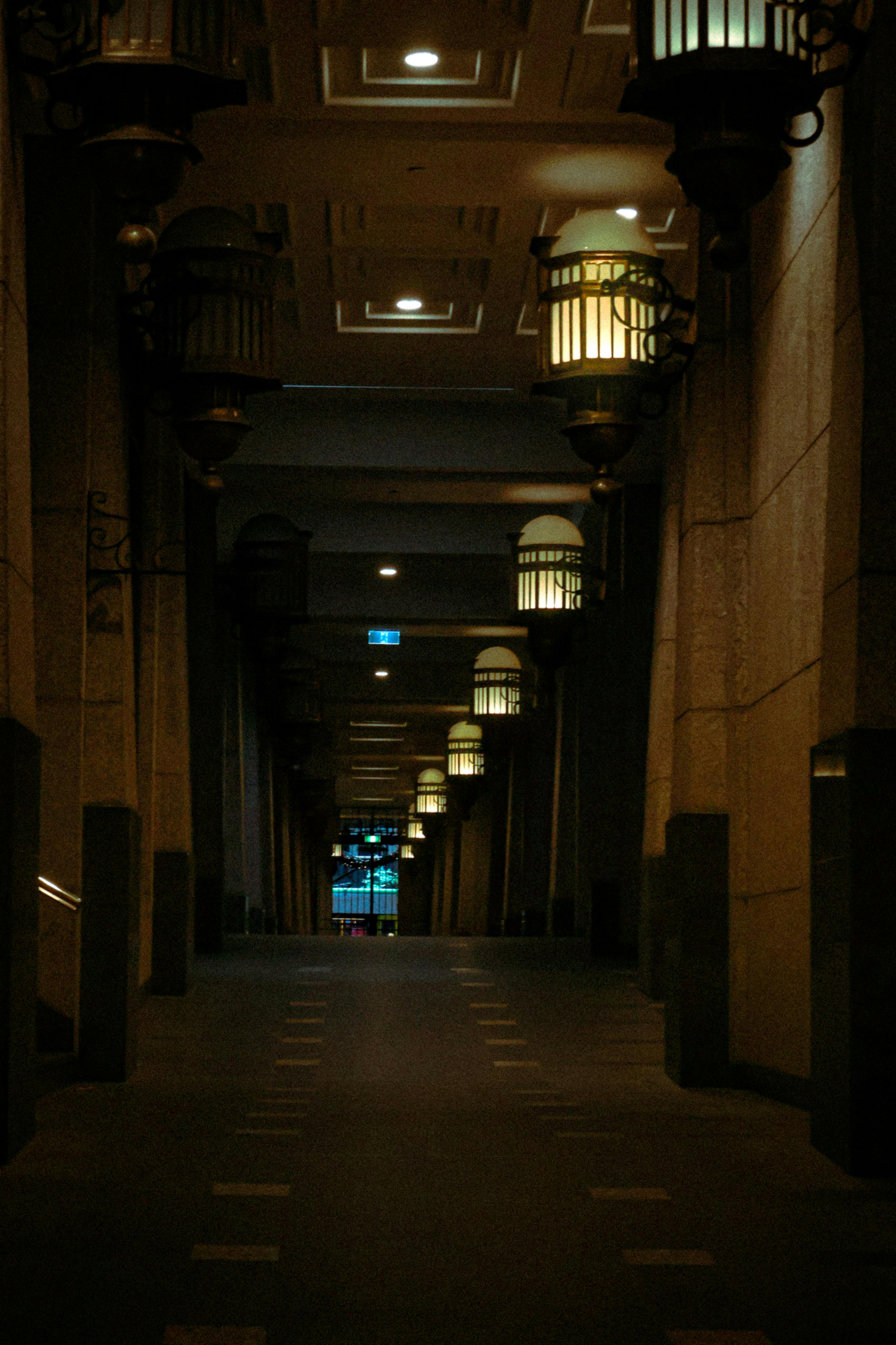 Free Atmospheric image of an indoor corridor with hanging lanterns and dim lighting. Stock Photo