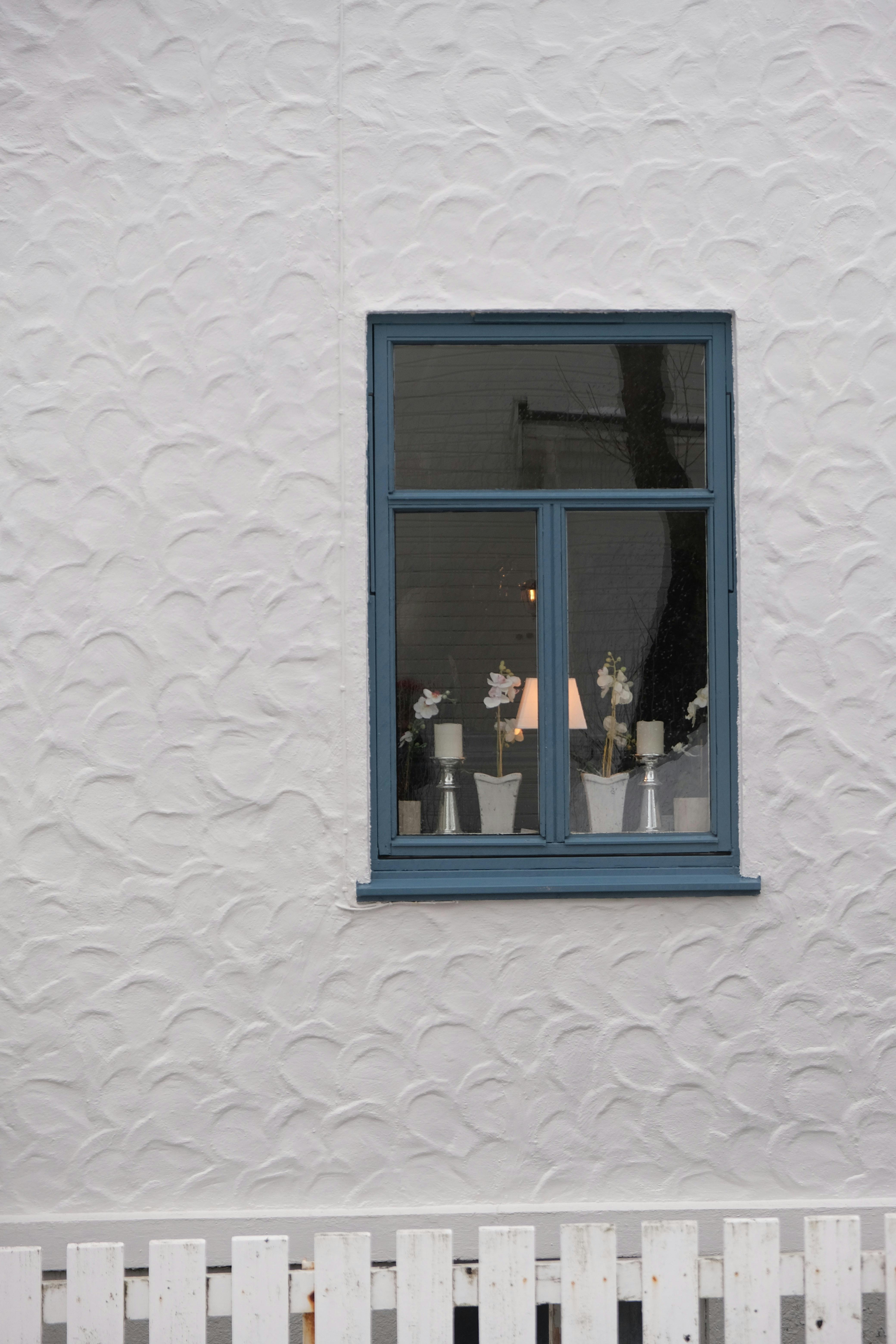 Kostnadsfria Närbild av ett fönster med blå lister och invändig dekor i en vit stuckaturvägg. Stock foto