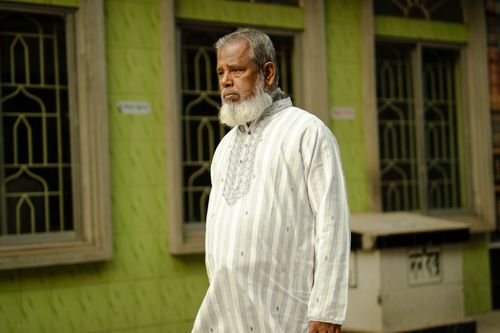 Free Senior man walking by a traditional building in urban area. Stock Photo