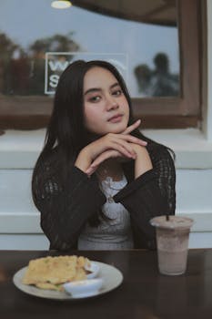 一名穿着黑色开衫的女子在咖啡桌旁摆放着食物和饮料，营造出轻松的氛围