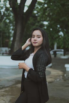 一位自信的女士身着时尚黑色开衫，在户外摆着姿势