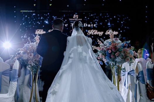 Romantic indoor wedding scene with the bride in a flowing gown and groom walking down the aisle.