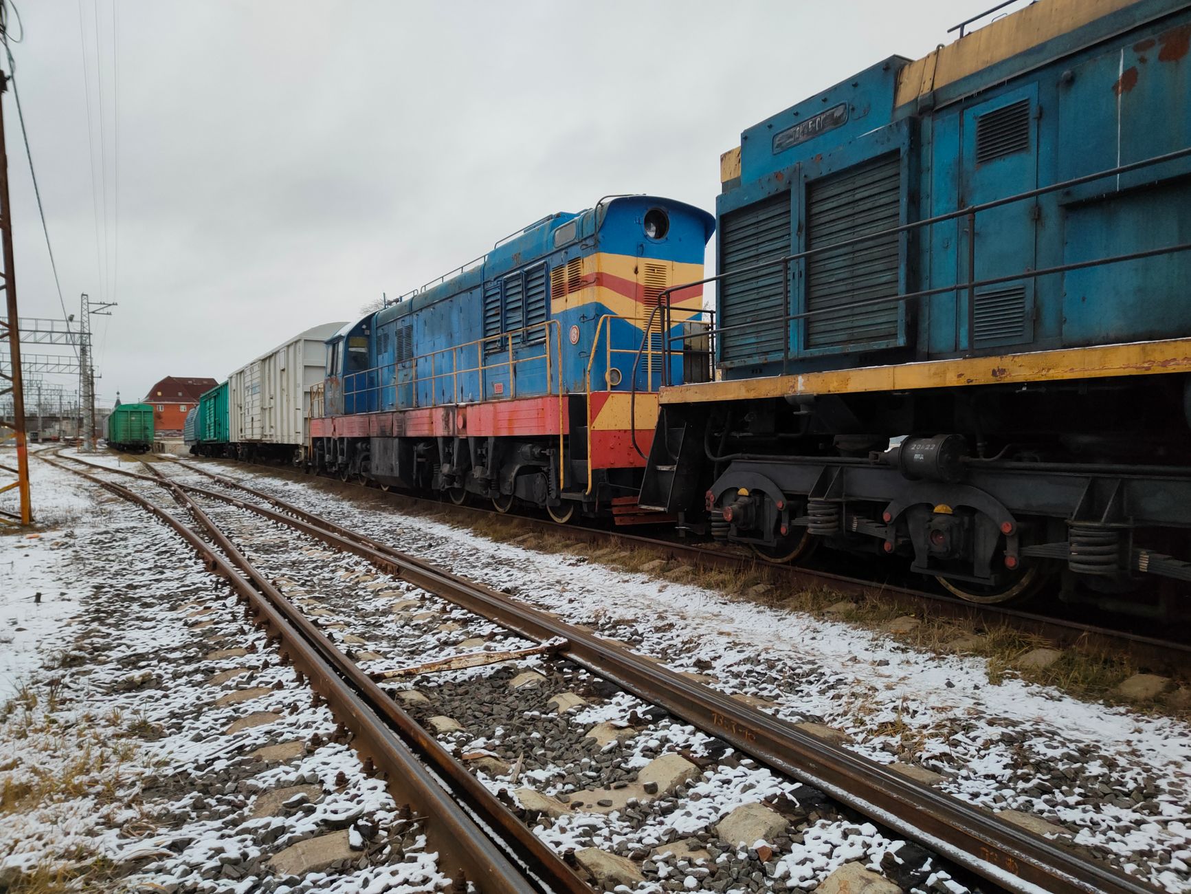 Colorful freight trains parked on snowy tracks, winter day scene.