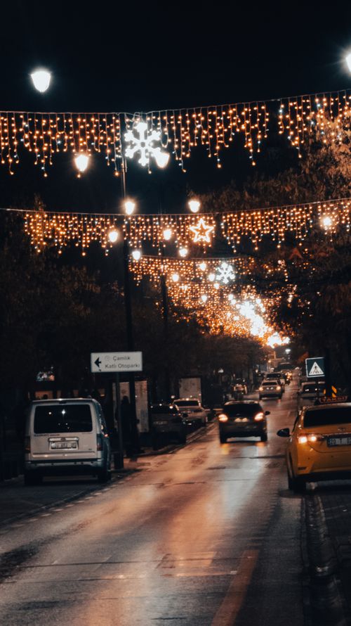Free A city street adorned with festive holiday lights at night, creating a warm atmosphere. Stock Photo