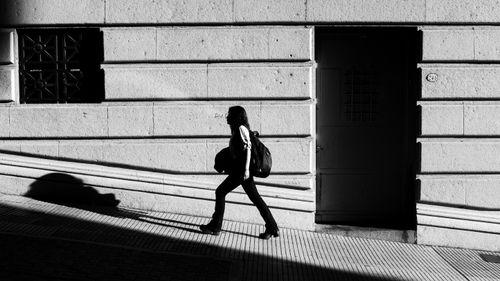Free Striking black and white image of a woman walking, casting a shadow on an urban street in Buenos Aires. Stock Photo
