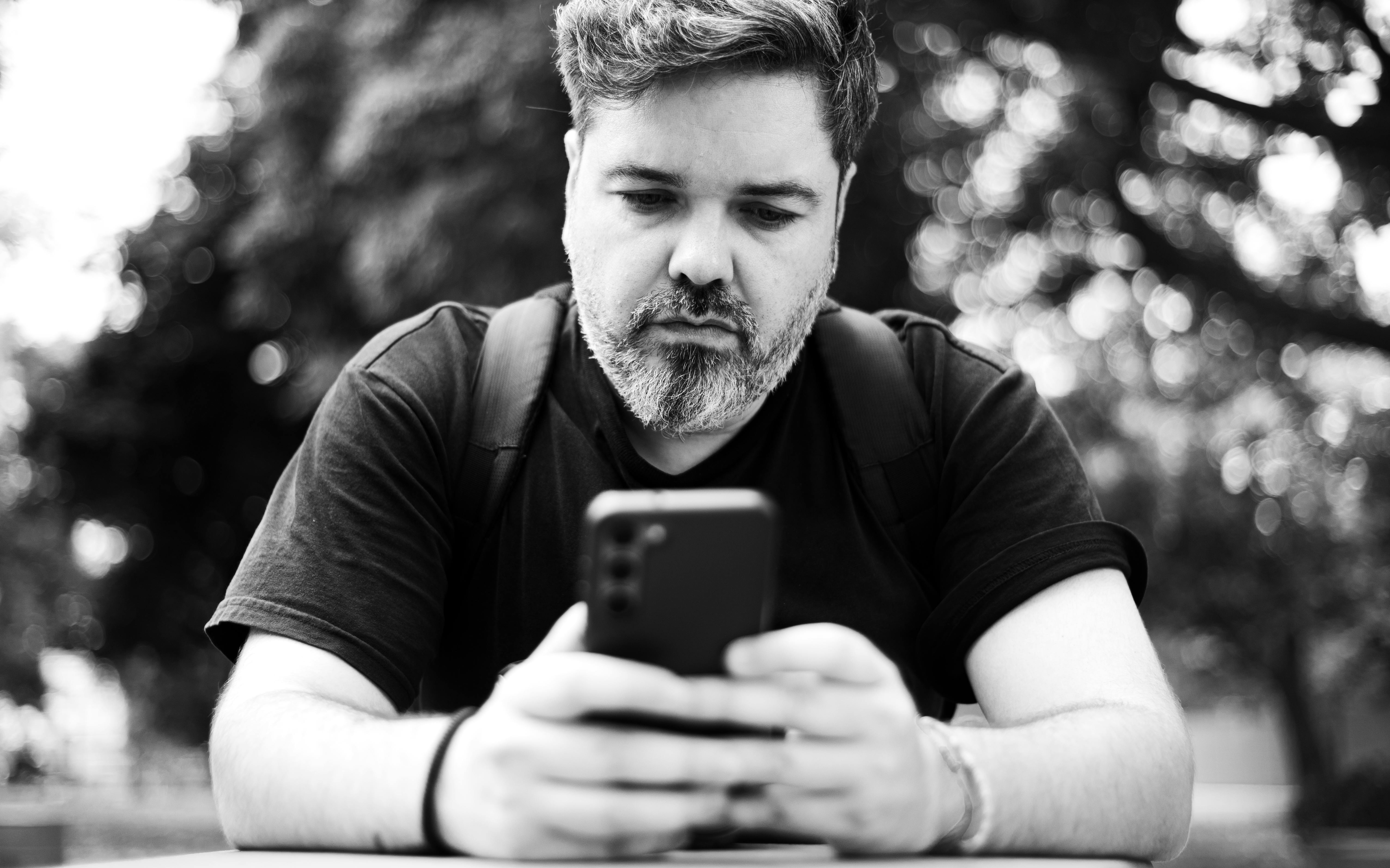 grátis Fotografia em preto e branco de um homem usando um smartphone em um parque em Buenos Aires, Argentina. Foto profissional
