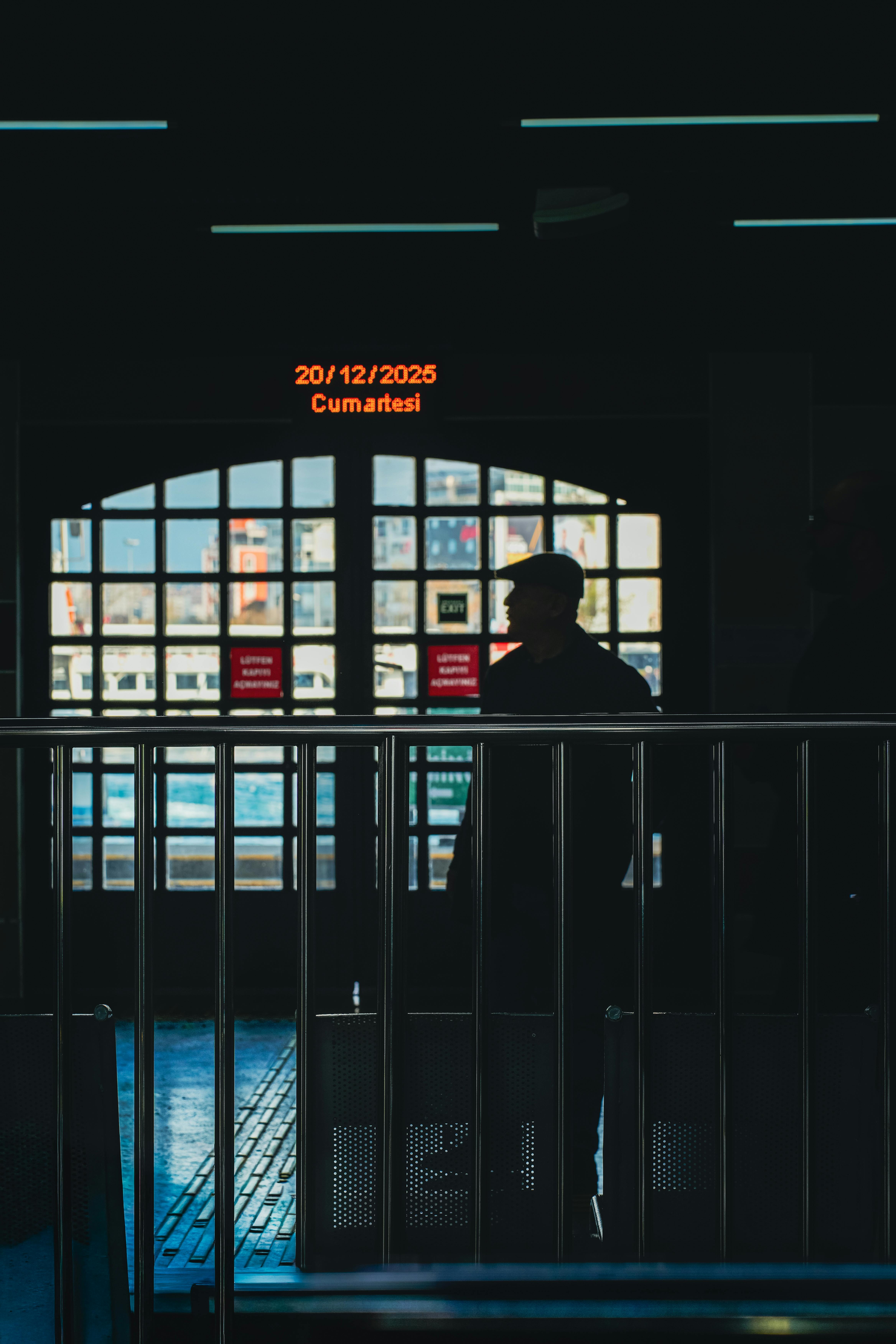 grátis Uma figura sombria está de pé dentro de um terminal de balsas, com um visor digital marcando a data 20/12/2025. Foto profissional