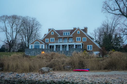 Beautiful lakefront house with rustic design surrounded by bare trees in winter.