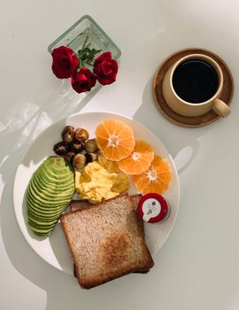 Delicious breakfast setup with avocado, scrambled eggs, toast, and coffee.