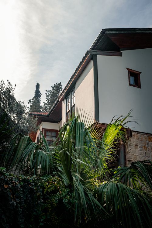 Free A charming house exterior surrounded by lush greenery under a clear sky, creating a serene and inviting atmosphere. Stock Photo