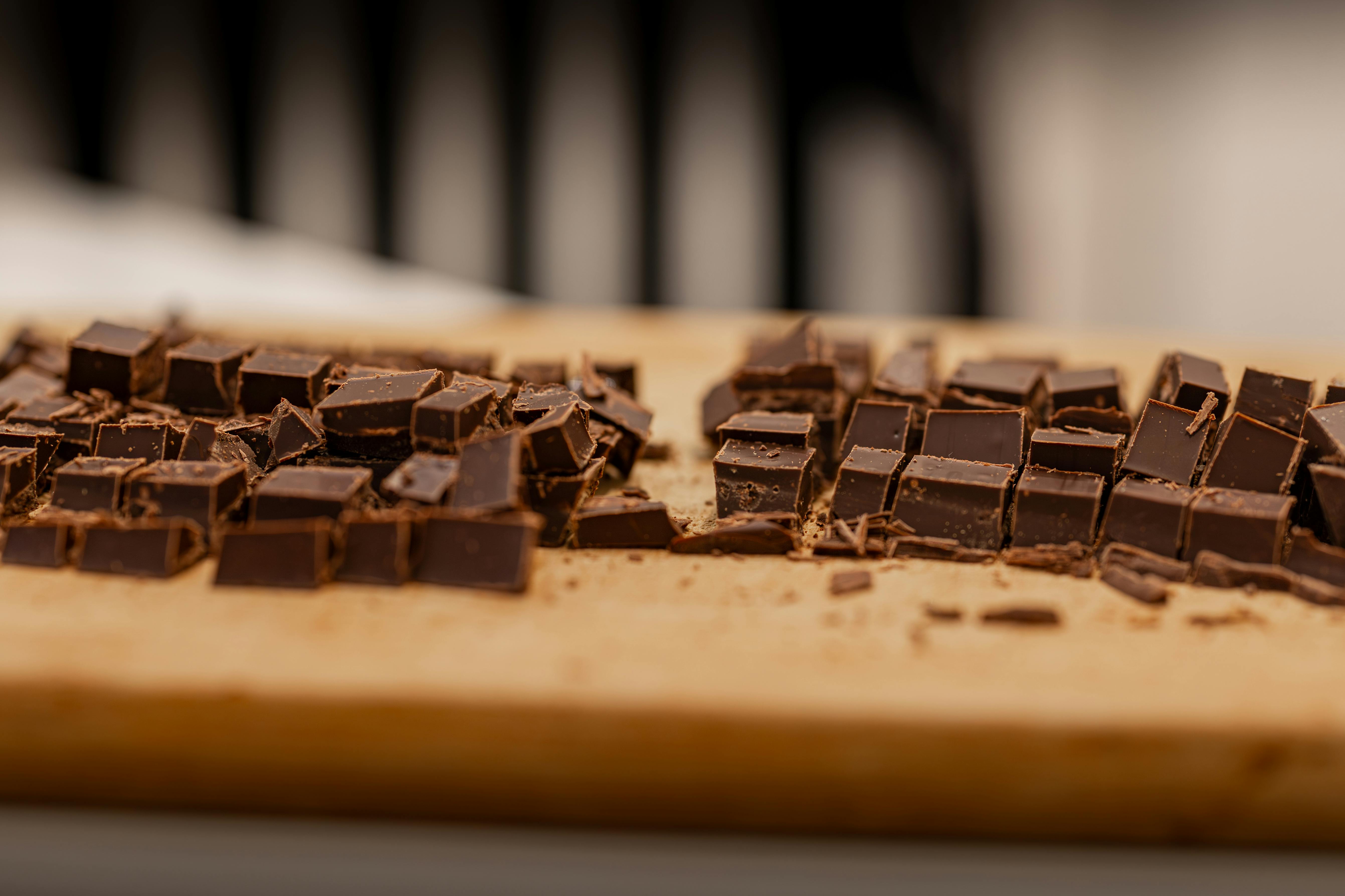 Sliced dark chocolate pieces on a wooden cutting board, perfect for dessert recipes.