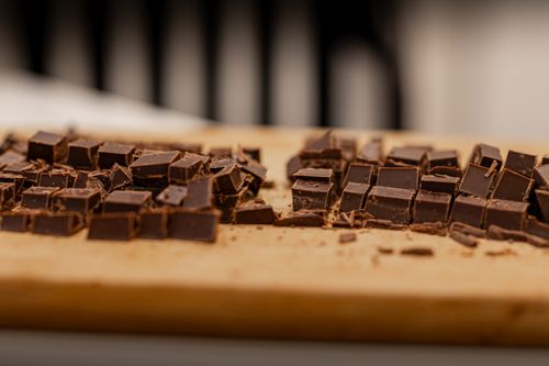 Free Sliced dark chocolate pieces on a wooden cutting board, perfect for dessert recipes. Stock Photo