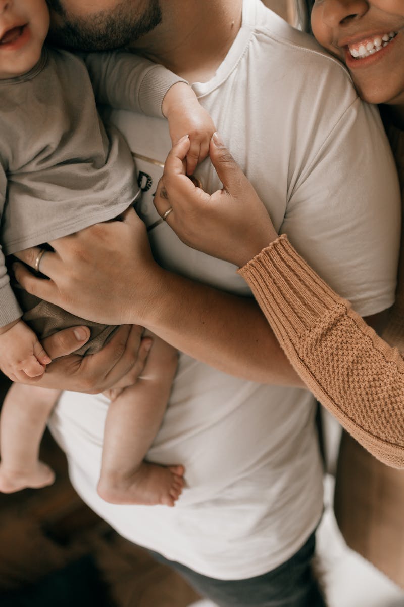 A loving family scene with parents holding a baby, captured in a warm, intimate setting.