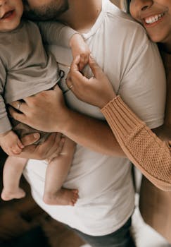A loving family scene with parents holding a baby, captured in a warm, intimate setting.