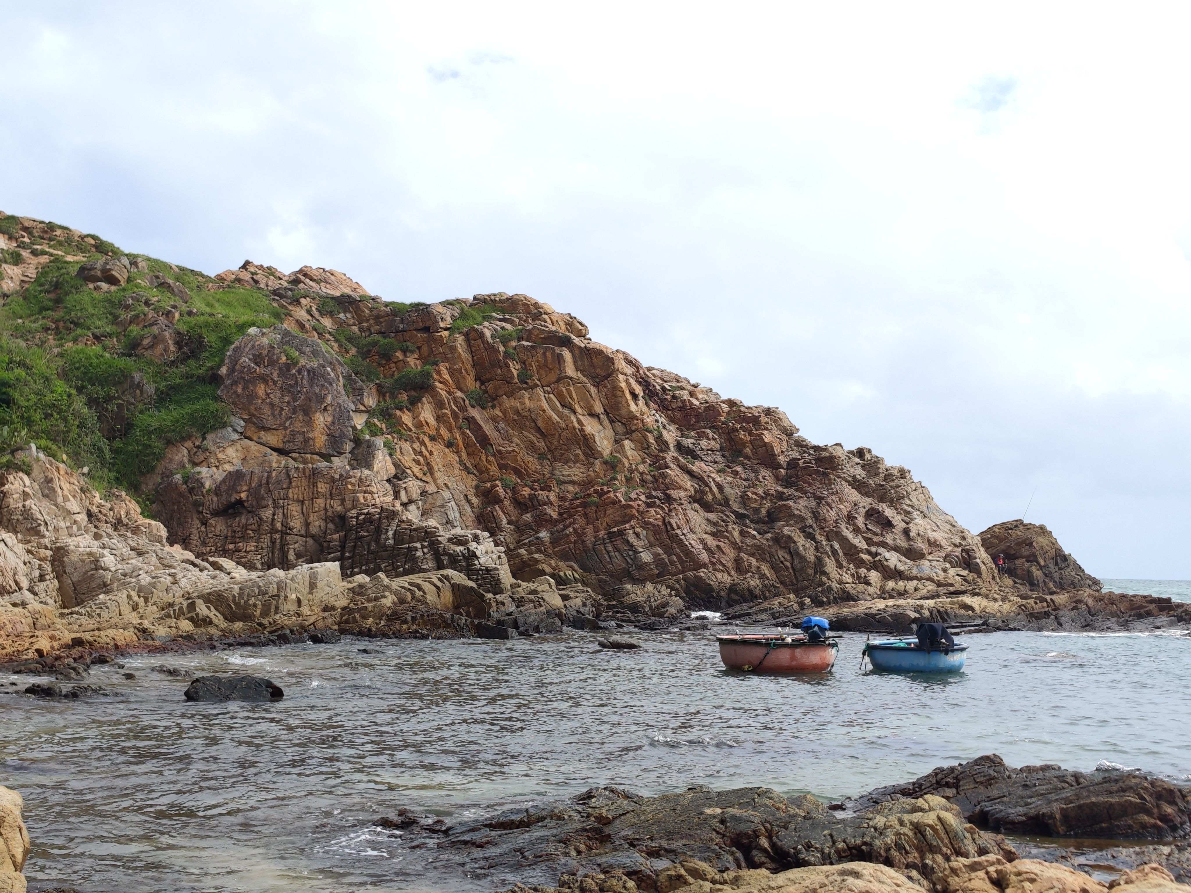 Two boats anchored by a rocky coastline in Phú Yên, Vietnam, showcasing tranquil seascape.