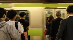 在日本，乘客们正在等待火车快速通过车站，捕捉每天的通勤时刻