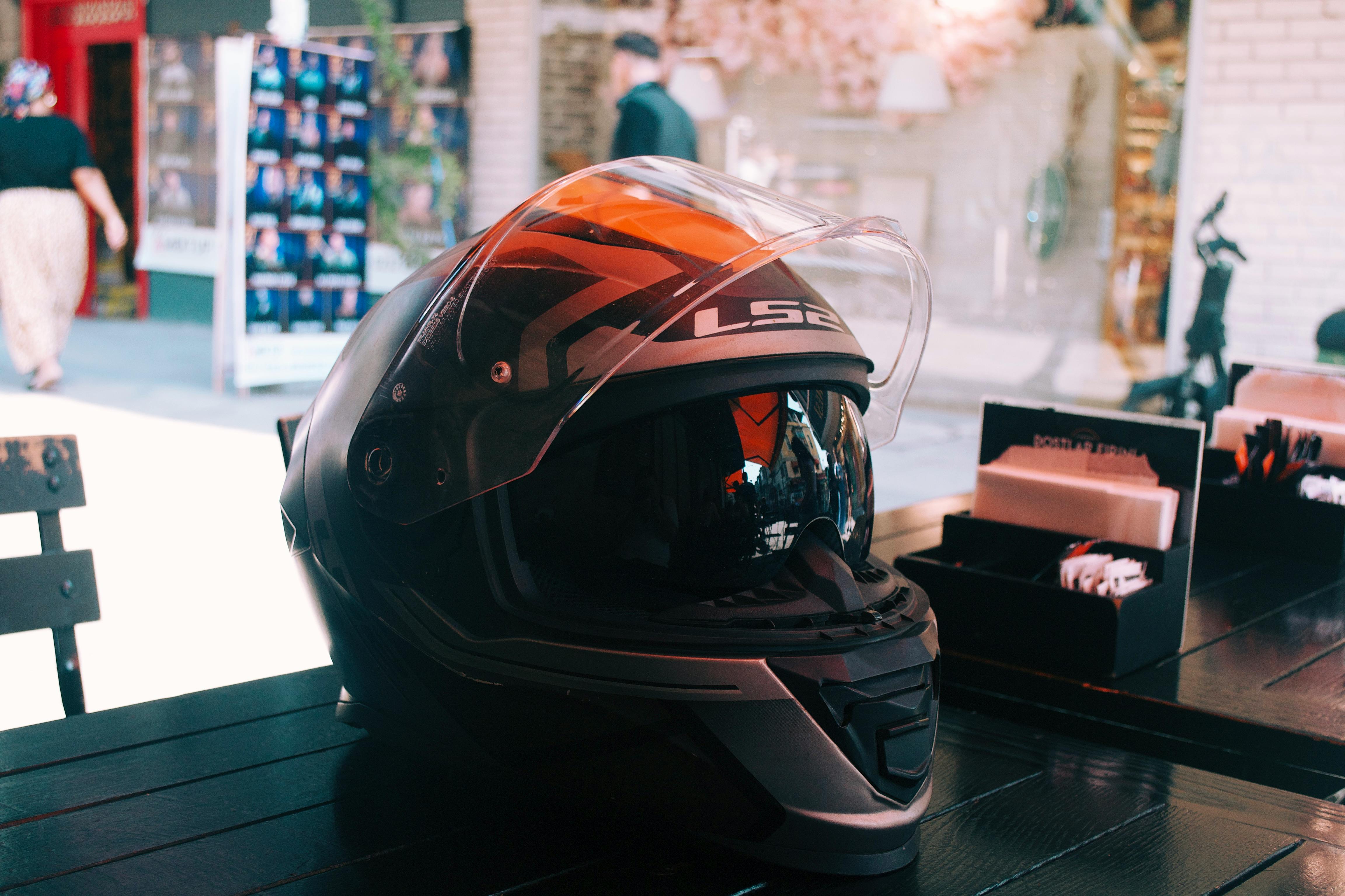 LS2 motorcycle helmet on a black cafe table outdoors, with blurred background.