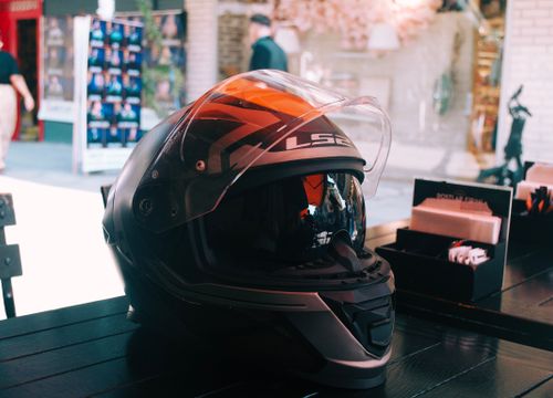 Casque moto intégral noir et orange, visière fermée, posé sur une table