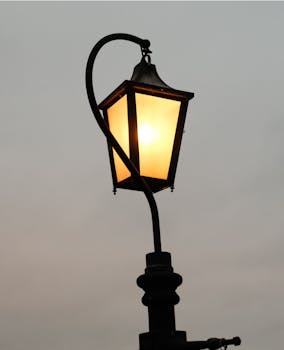 A vintage street lamp glowing against a moody, overcast sky creating a nostalgic atmosphere.